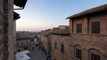 A narrow street with traditional brick buildings, arched doorways, and a clear sky.
