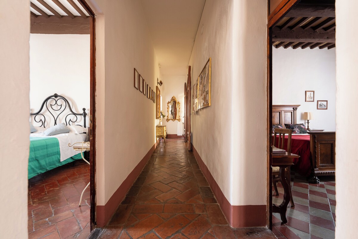 A narrow hallway with a bed on the left, a wooden cabinet on the right, and a tiled floor.