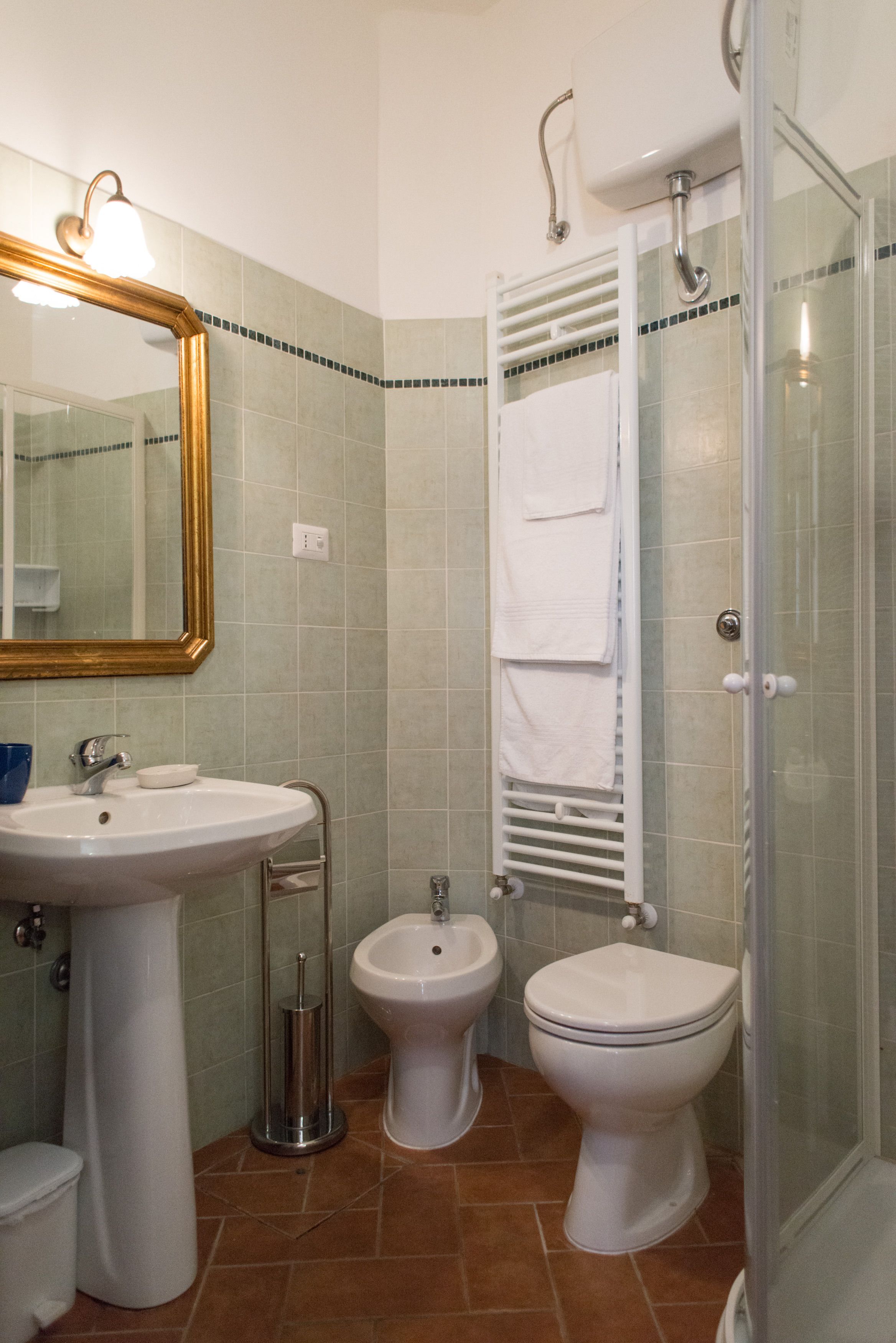 A bathroom with a sink, bidet, toilet, and shower.