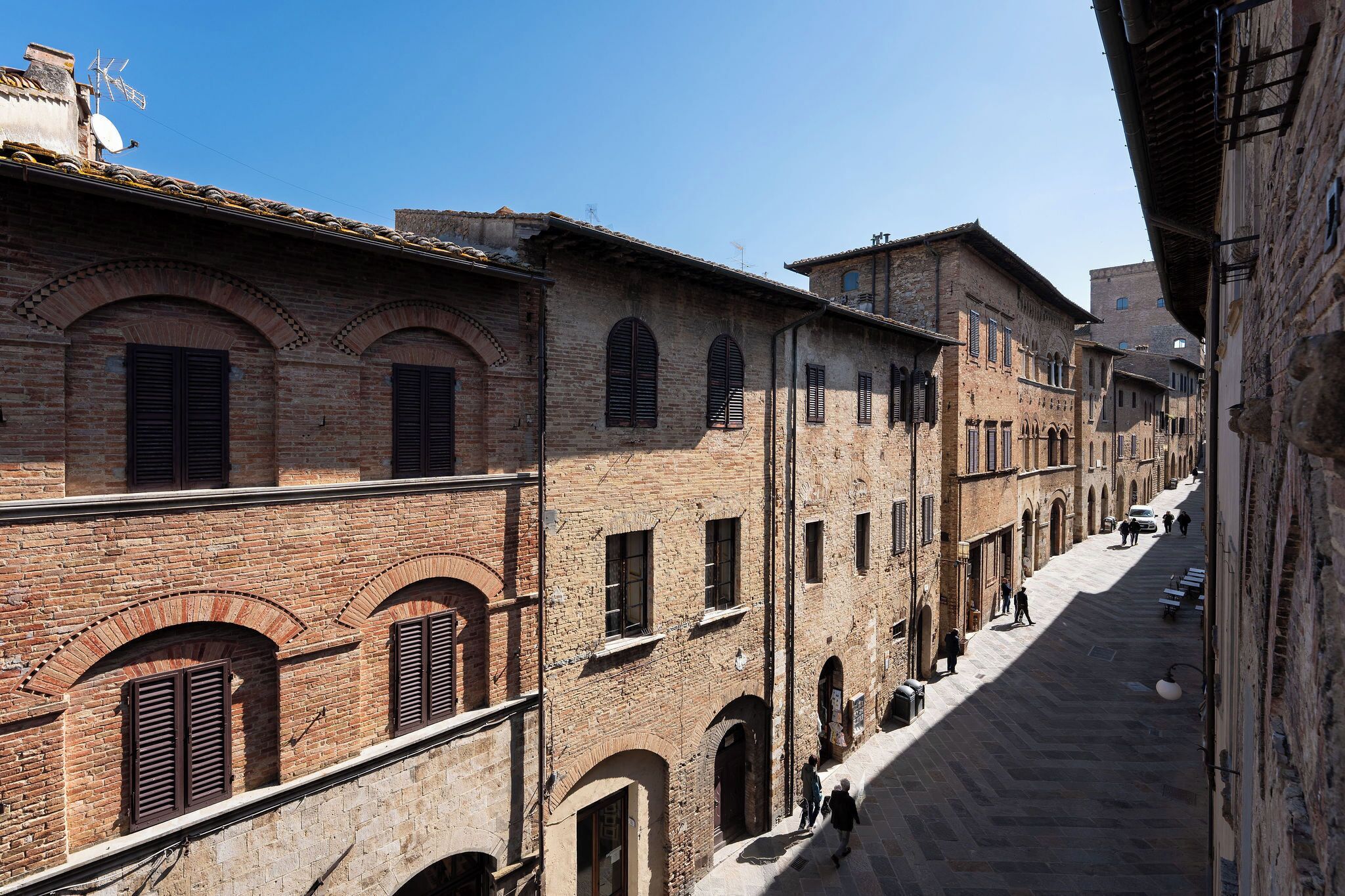 A narrow street lined with historic buildings featuring arched windows and brick facades.