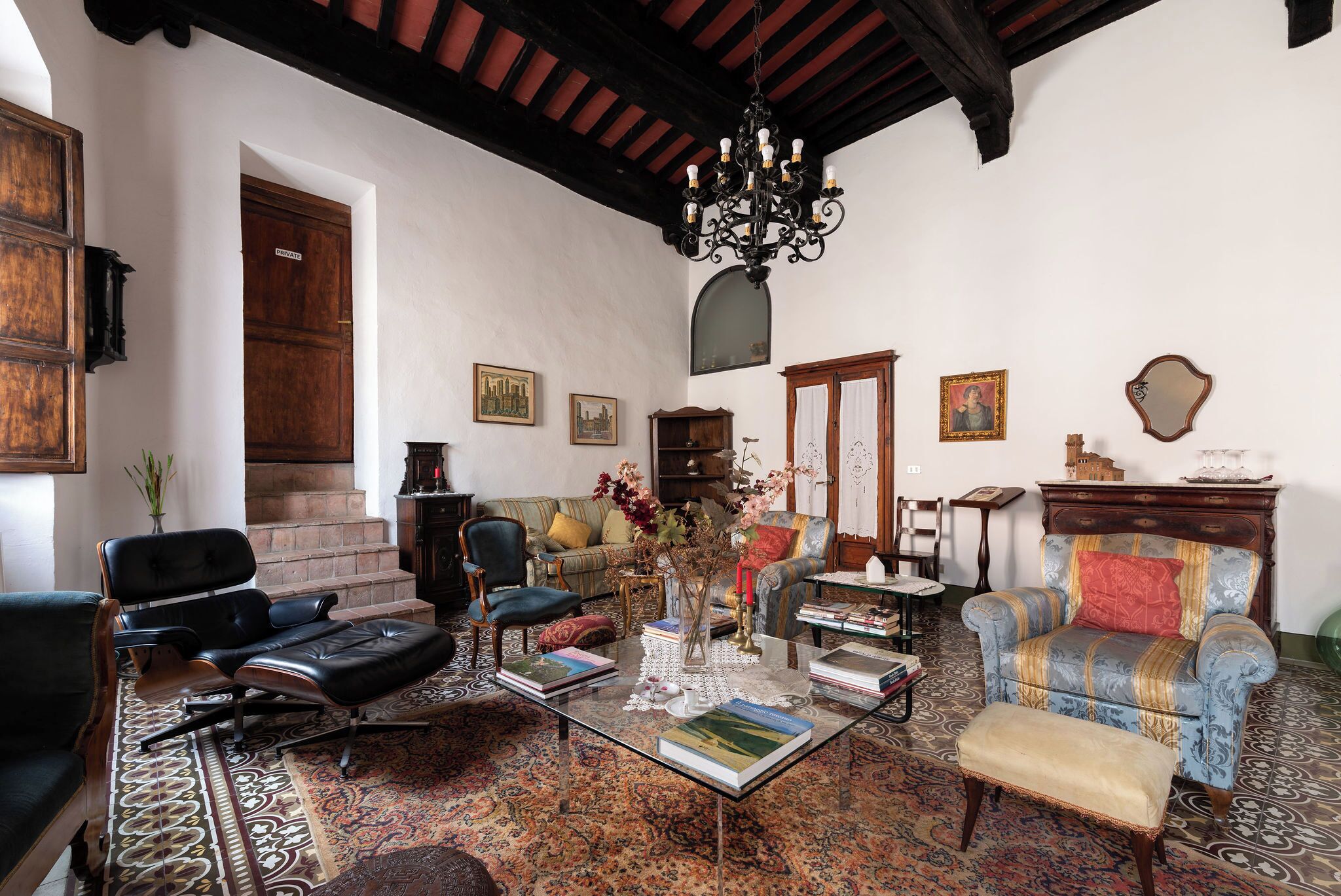 A traditional room with a sofa, chairs, a coffee table, and a staircase.
