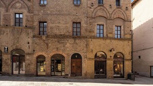 A historic building with multiple arched windows and doors, a brick facade, and a flat roof. - Residenza d'Epoca Palazzo Buonaccorsi (San Gimignano)