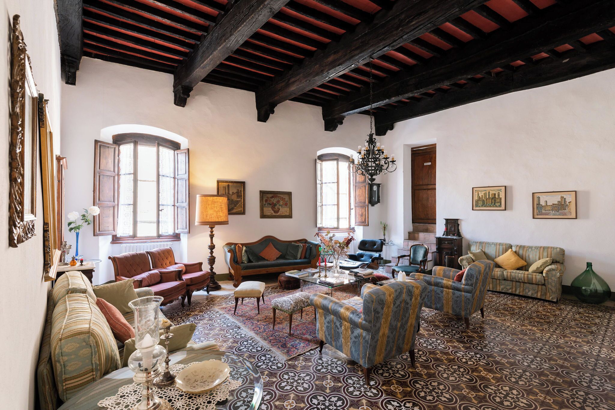 A spacious living room with multiple seating areas, large windows, and a patterned floor.