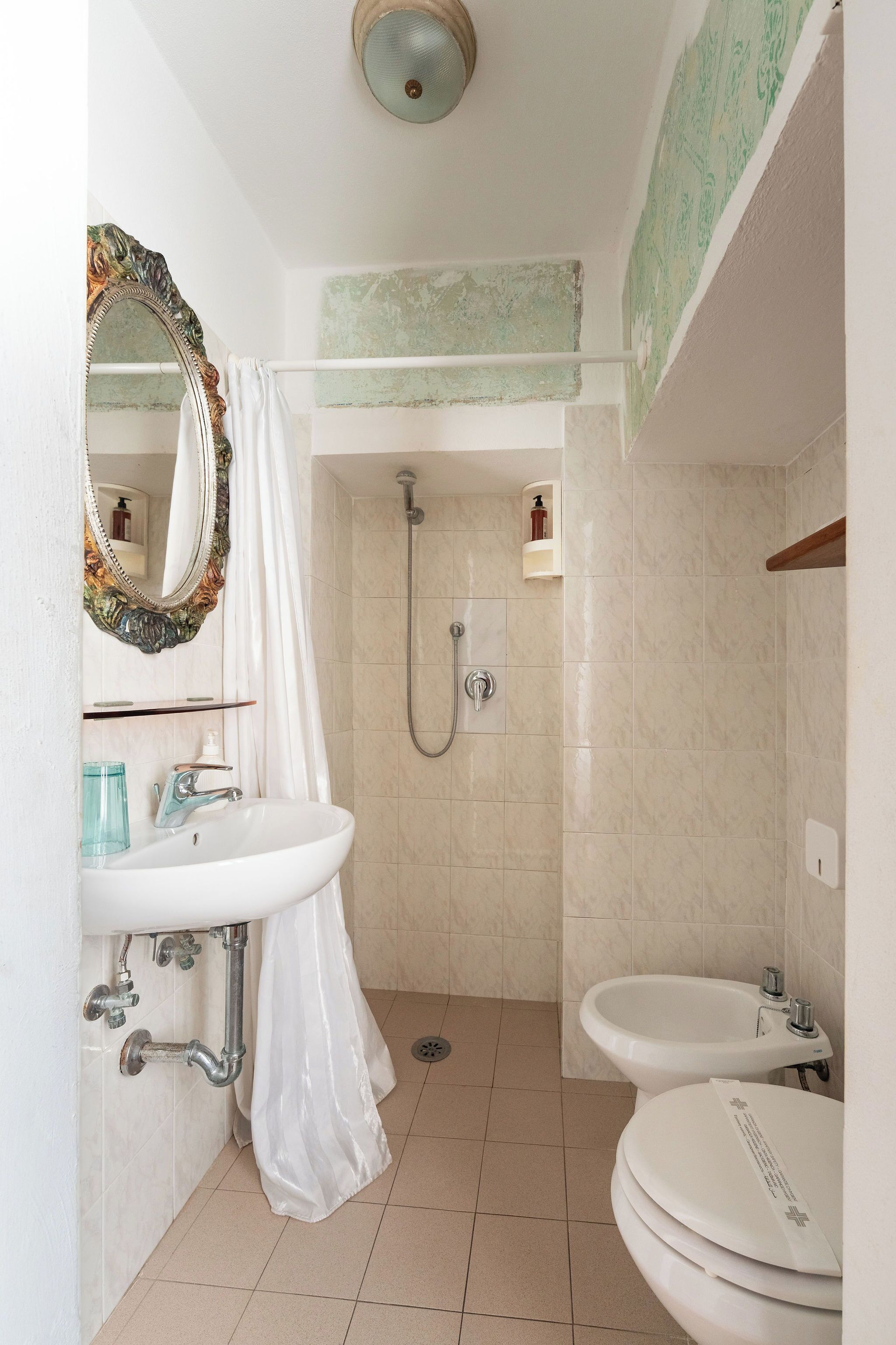 A bathroom with a shower, two sinks, a mirror, and a toilet.