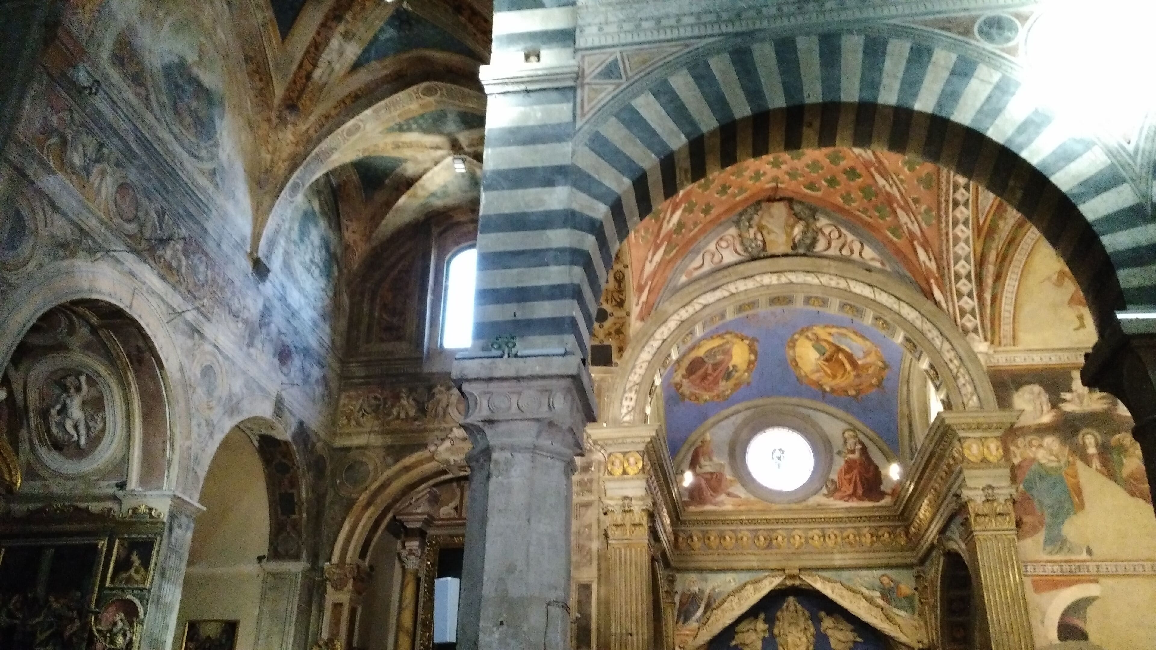 An interior with arched ceilings and detailed frescoes.