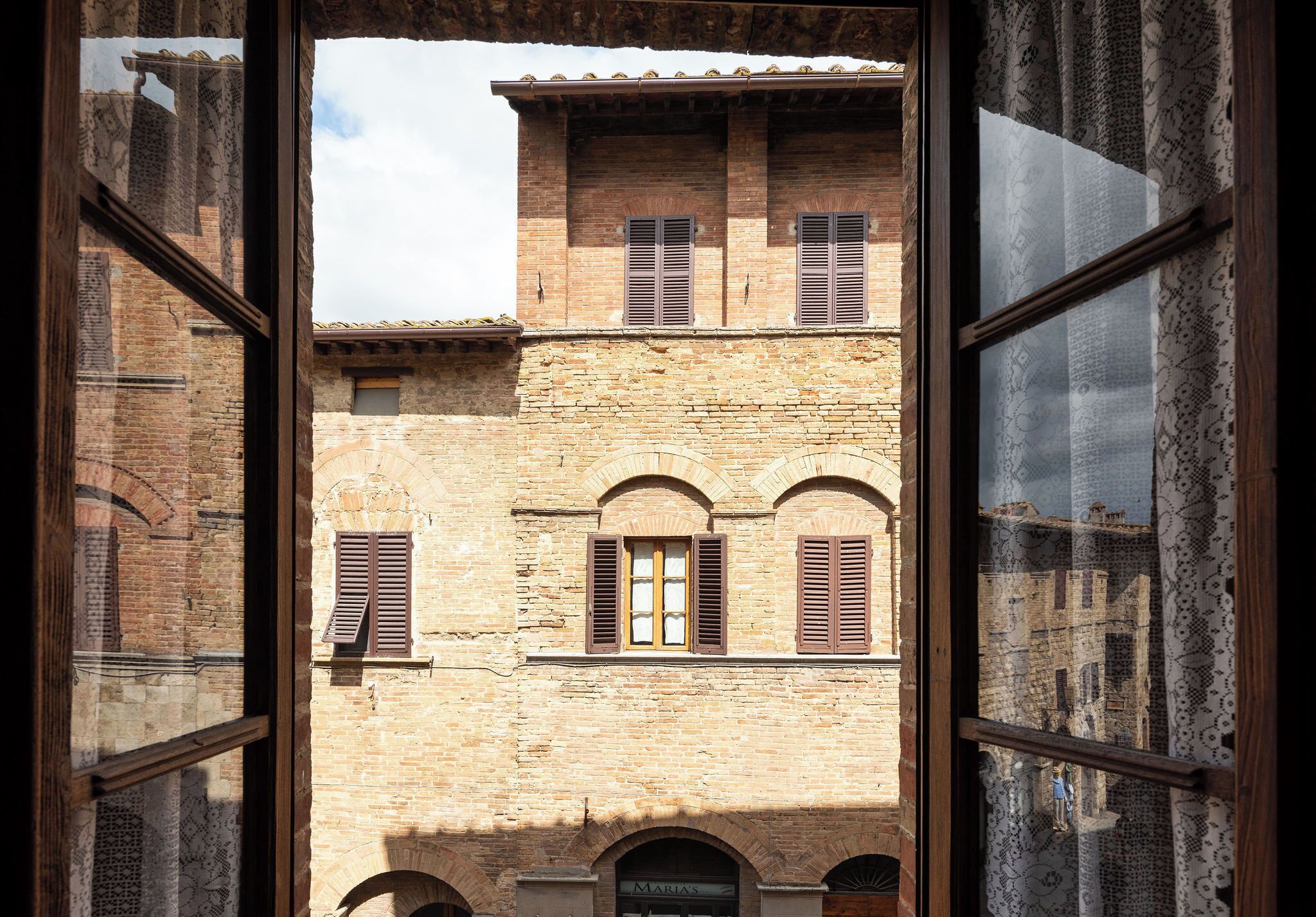A view through a window of a building with arched windows and a brick facade.