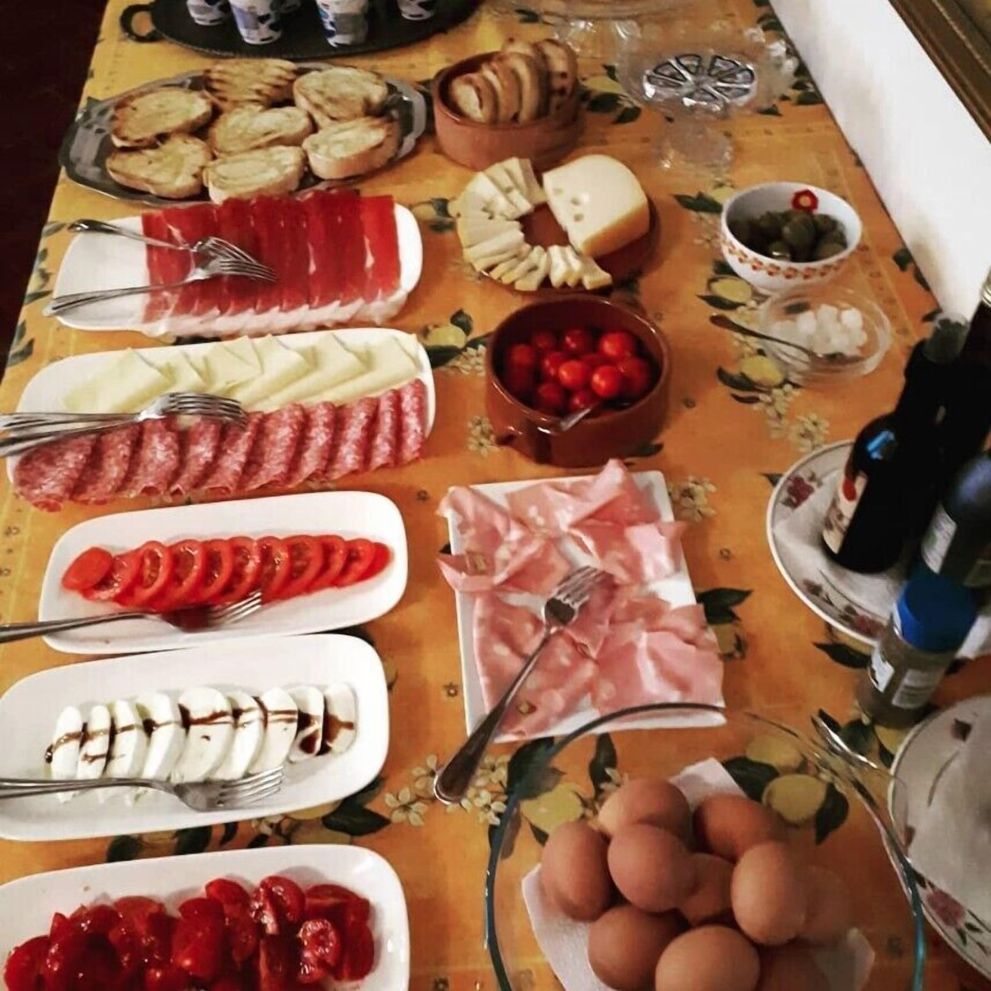 Un tavolo imbandito con salumi, formaggi e frutta.