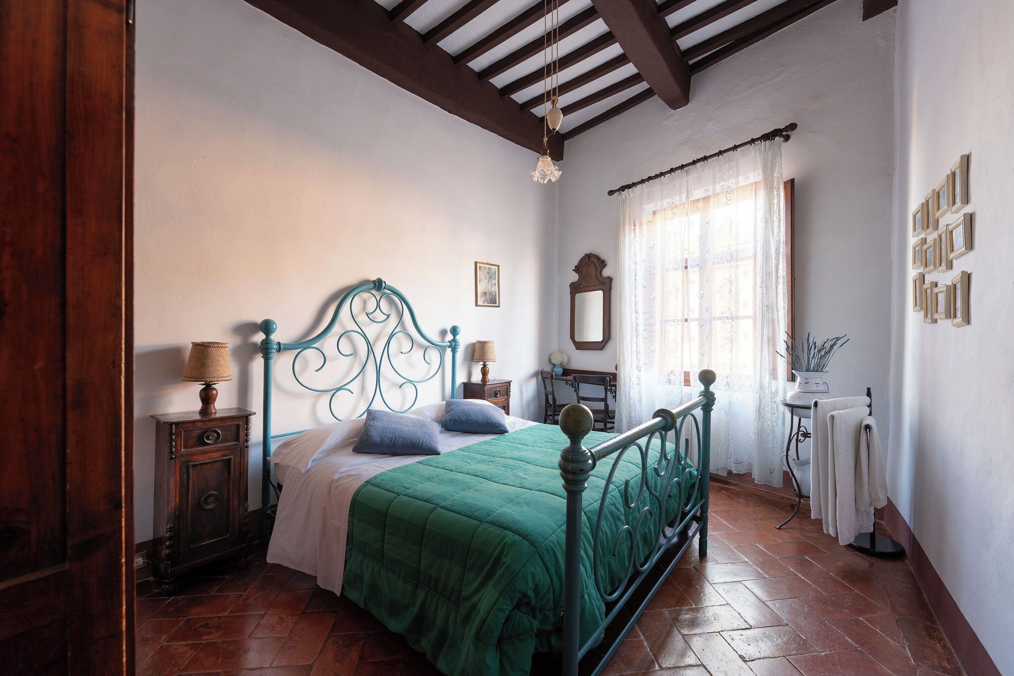 Une chambre à coucher avec un lit, des tables de chevet, un miroir, un radiateur et une fenêtre avec des rideaux.