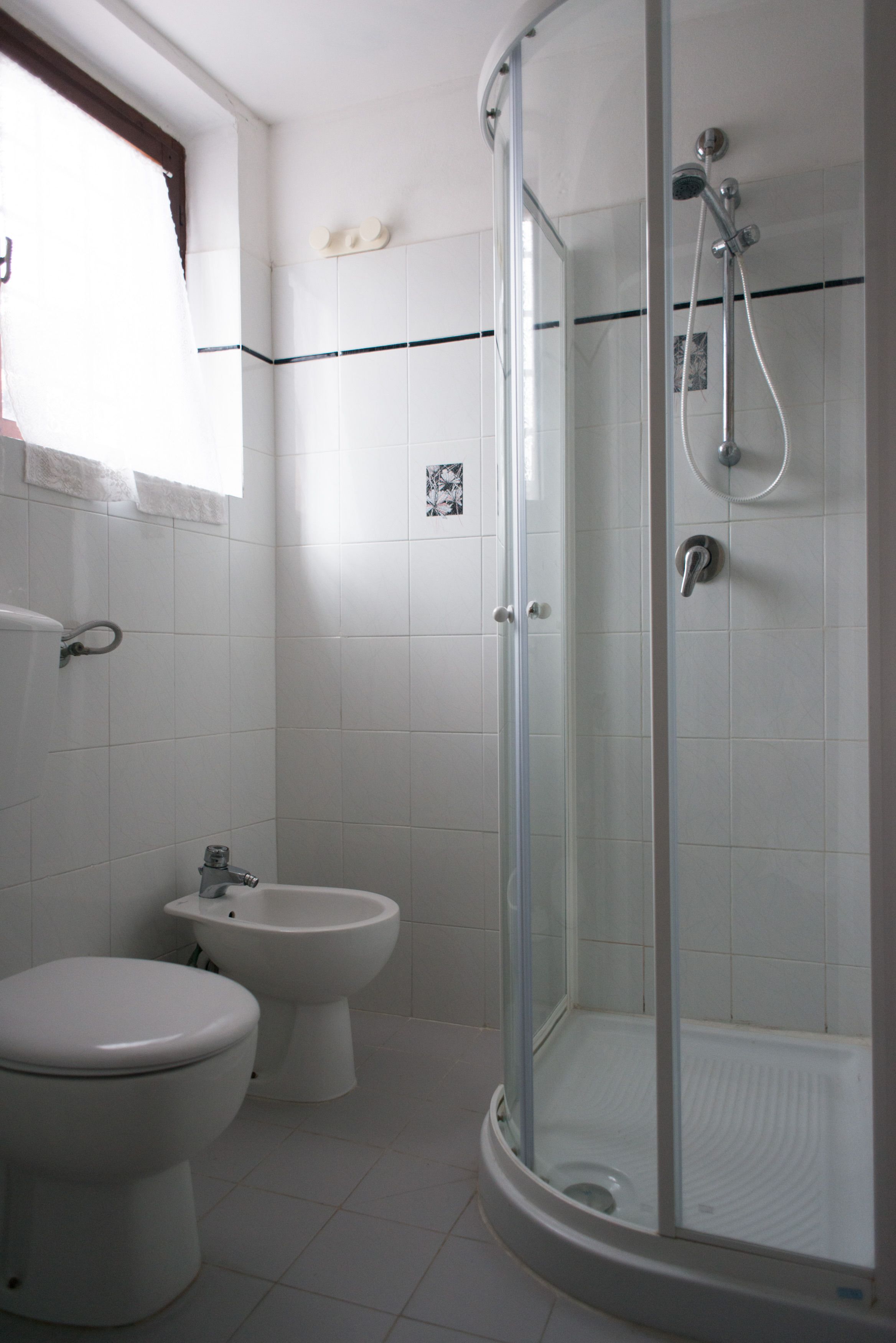 A bathroom with a toilet, bidet, and a glass-enclosed shower area.