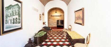 Un pasillo con piso de cuadros, una chimenea y cuadros enmarcados en las paredes.