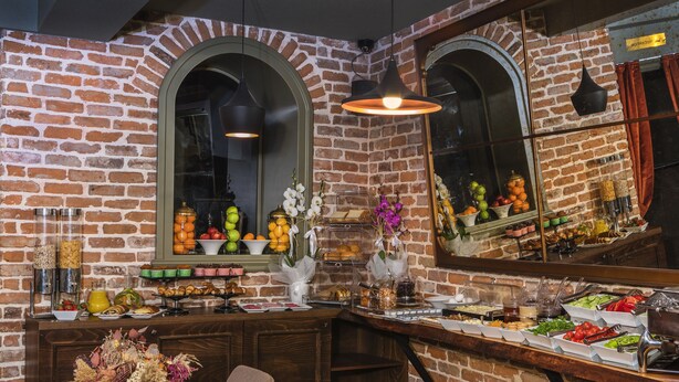 A brick-walled room with a breakfast bar, a dining table, and a mirror reflecting the room.