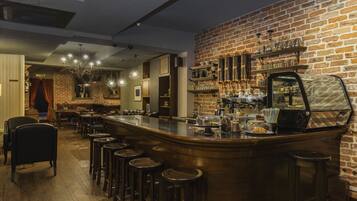 A bar area with a brick wall, stools, and a counter with various items.