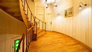 A wooden staircase leading to a second floor, a chandelier, and a framed picture on the wall.