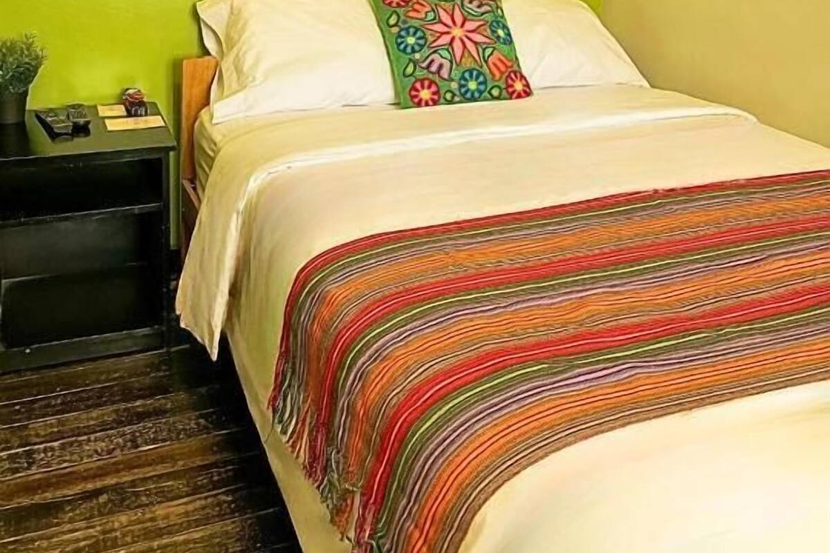 A hotel room with a bed, a nightstand, a mirror, and a green wall.