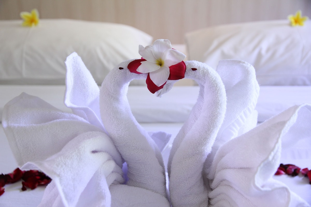 A bed with white linens and a decorative flower arrangement.
