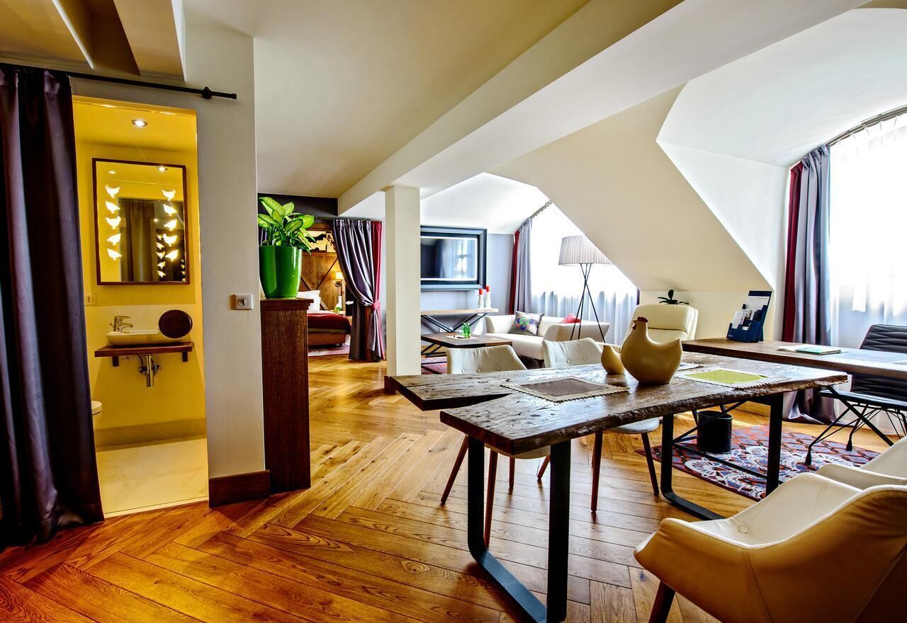 Ein geräumiges Loft-Zimmer mit Holzboden, Esstisch, einer Couch und einem Fernseher.