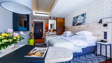 Una habitación de hotel moderna con cama, mesita de noche, lámpara y teléfono en la pared.