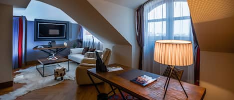A modern loft apartment with a high ceiling, a cozy seating area with a sofa and armchairs, a dining table with a lamp, and a large window with curtains.