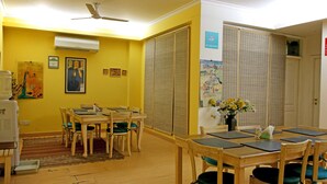 Un comedor con mesas y sillas de madera, un equipo de aire acondicionado y un ventilador de techo.