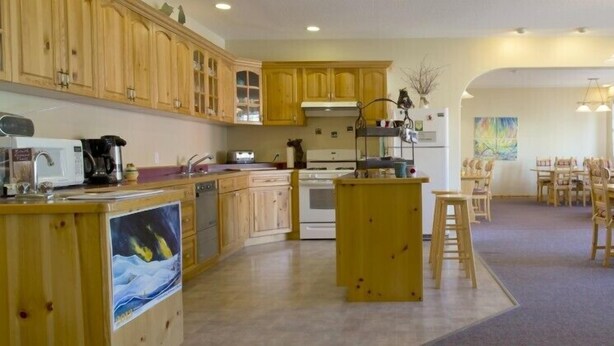 Una cucina con mobili in legno, un'isola centrale e un'area pranzo con sedie e tavolo in legno.