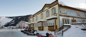 A hotel with a signboard, wooden exterior, and a staircase leading to the entrance.