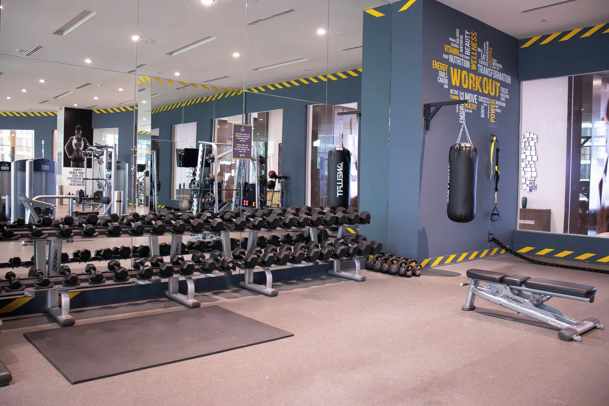 A gym with various exercise equipment, including dumbbells, a bench, and a punching bag.