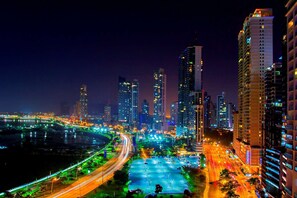 Un paisaje urbano nocturno con rascacielos iluminados y una autopista con mucho tráfico.