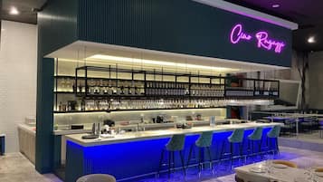 Eine moderne Bar mit einer Neonreklame, Flaschenregalen und Barhocker.