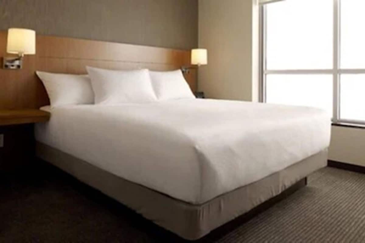 Hotellihuone, jossa on suuri sänky, kaksi yöpöytälamppua ja ikkuna.