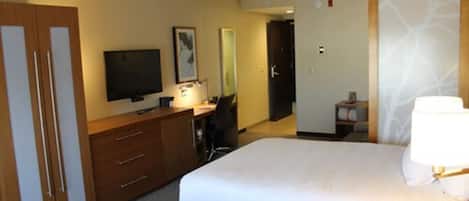 A hotel room with two beds, a desk, a television, a mirror, and a wardrobe.