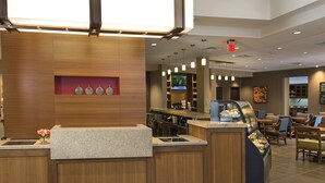A modern hotel lobby with a reception desk, seating area, and a television screen. - Hyatt Place Detroit/Novi (Novi)