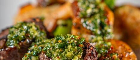 A plate with skewered meat and vegetables, garnished with a green sauce.