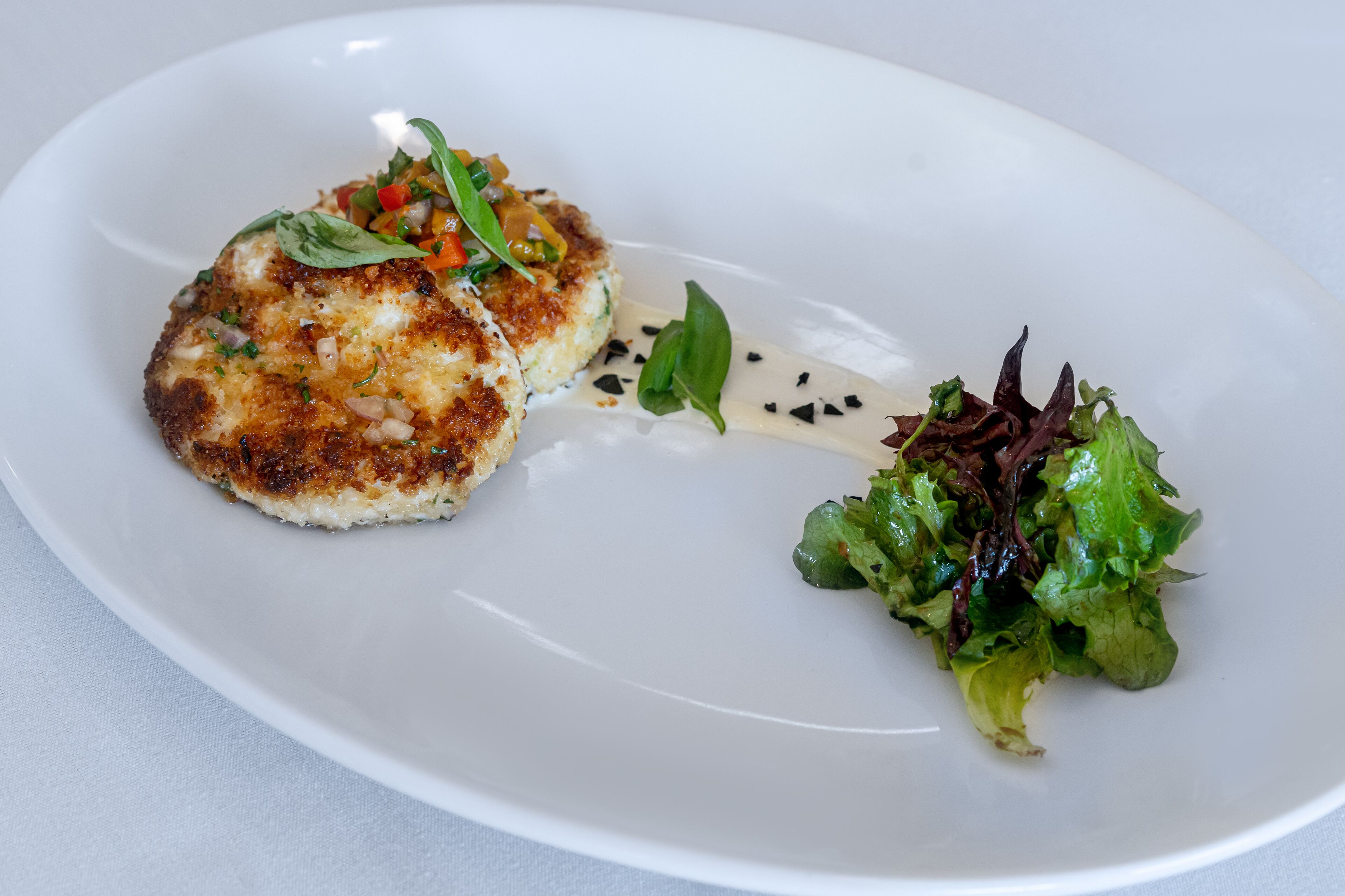 Un plato blanco con comida y una ensalada verde.