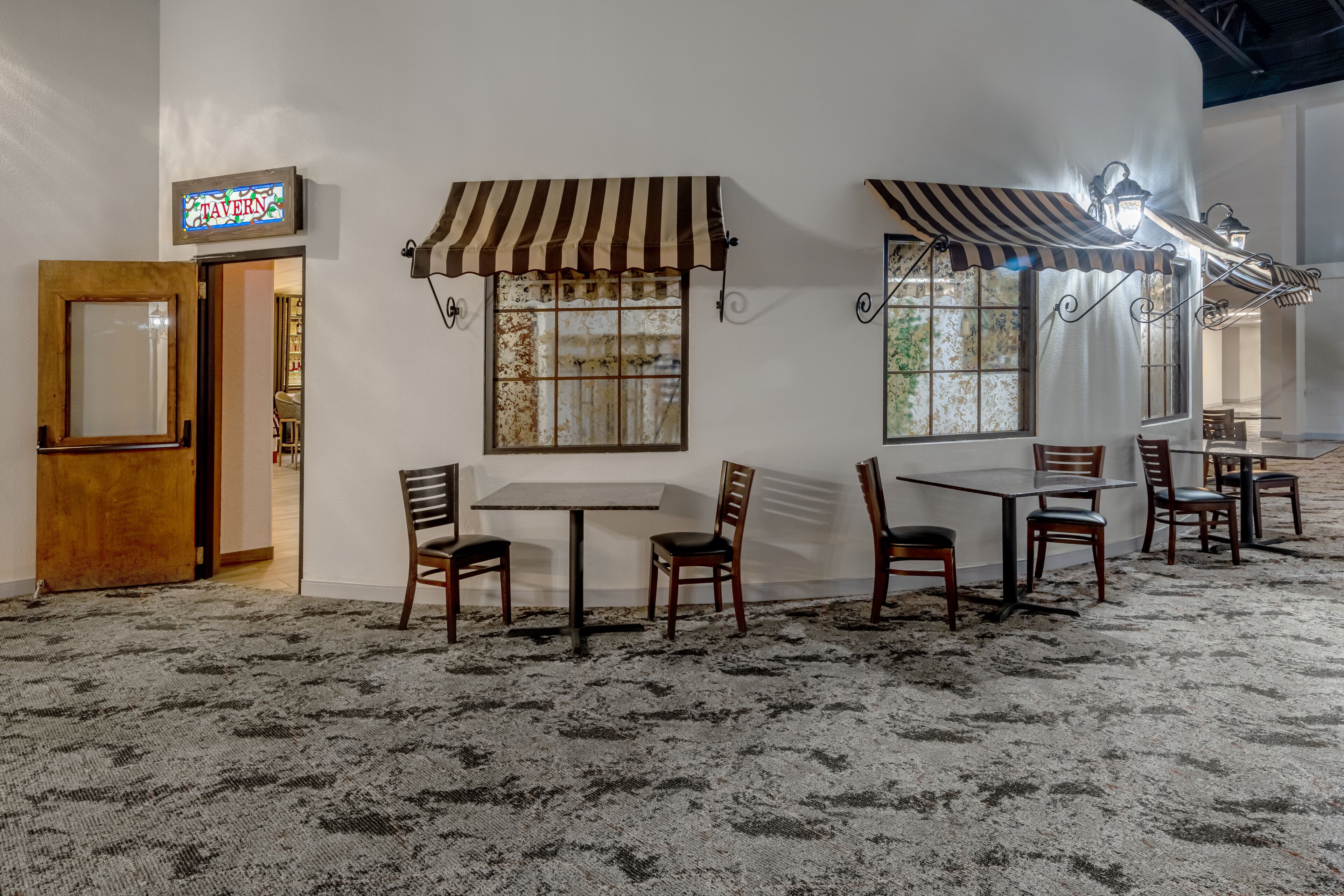 A restaurant interior with striped awnings, tables, and chairs.