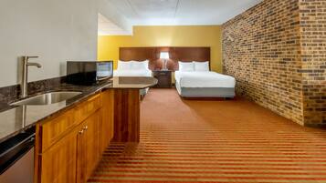 Habitación de hotel con cocina, una cama y una pared de ladrillo.