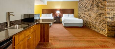 Habitación de hotel con cocina, una cama y una pared de ladrillo.