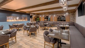 Restaurante com vigas de madeira, lareira e assentos modernos.
