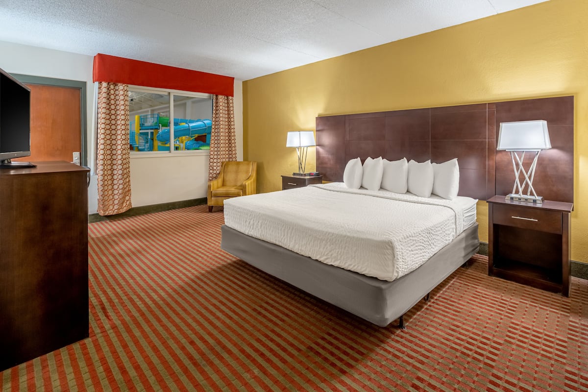 A hotel room with a large bed, a TV, a desk, and a chair.