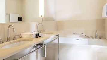 Een moderne badkamer met twee wasbakken, een badkuip en een spiegel.