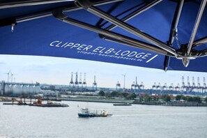 A view of the water with a boat and industrial structures in the background. - Clipper Boardinghouse – Hamburg-Holzhafen (Hamburg)