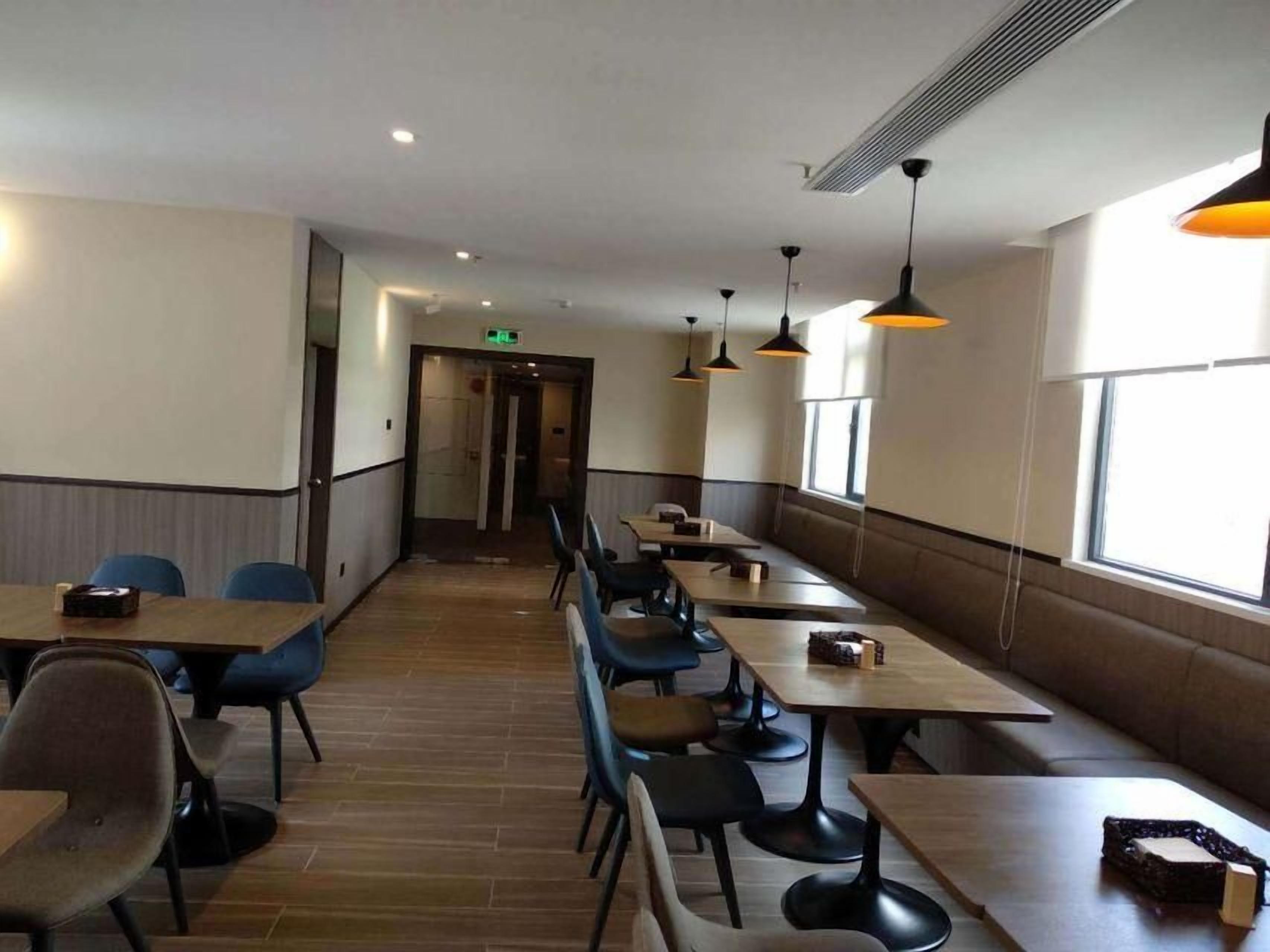 Une grande salle à manger avec des tables et des chaises, un couloir central et un mur entièrement vitré.