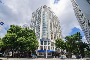 A high-rise hotel with a prominent sign, surrounded by trees and other buildings. - HanTing Hotel (Shenzhen Huaqiangbei Yannan Subway Station) (Shenzhen)