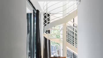 A modern interior with a spiral staircase, large windows, and a wooden bench.