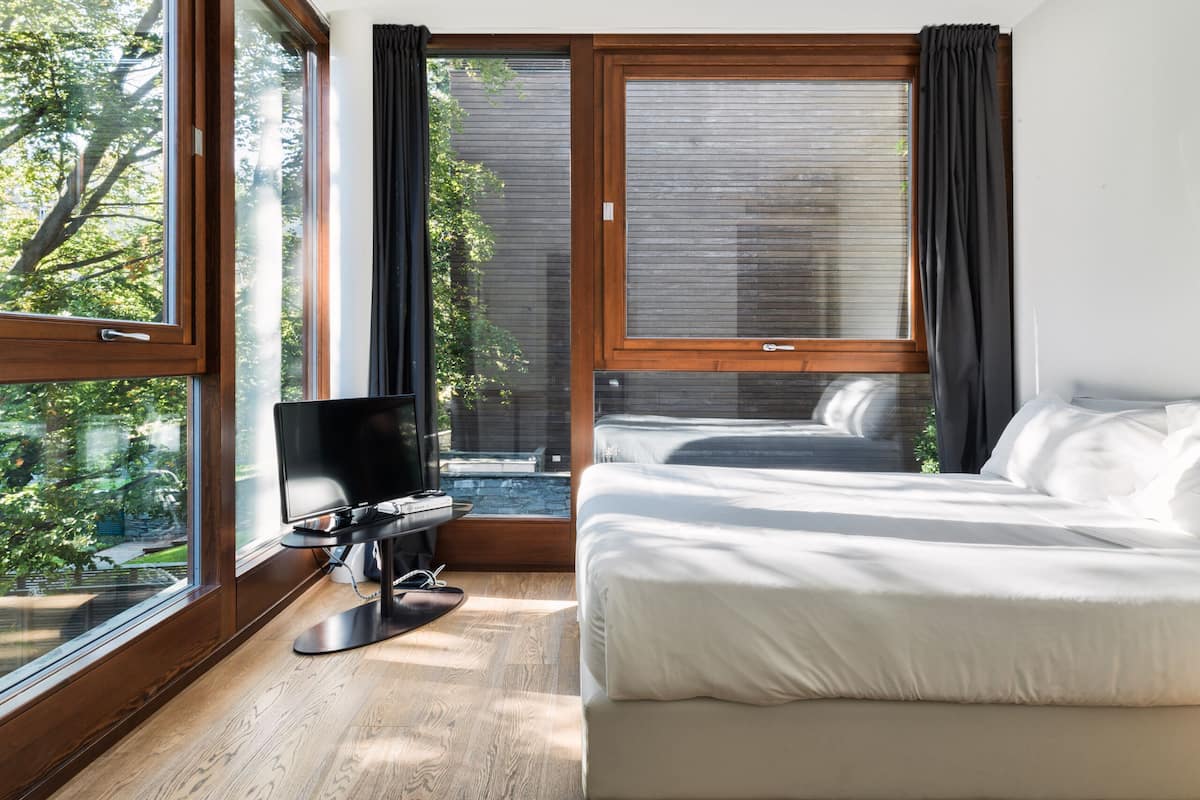 Une chambre à coucher avec un lit, une télévision et de grandes fenêtres.