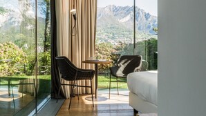 A modern bedroom with a large window, a bed, a table, and two chairs. - Casa sull'Albero (Malgrate)