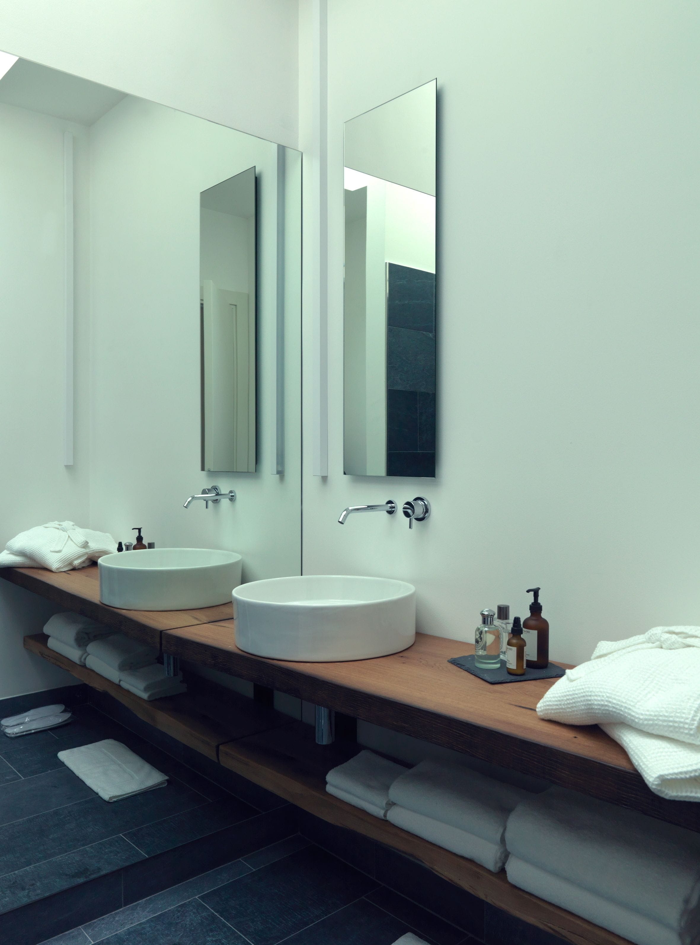 Une salle de bain moderne avec deux lavabos, de grands miroirs et un meuble-lavabo en bois.