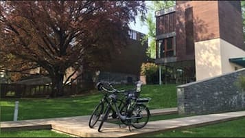Ein Fahrrad steht auf einem Betonweg, im Hintergrund ein Gebäude.
