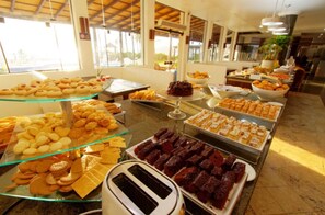 A buffet with various pastries and desserts displayed on glass trays and plates.
