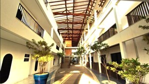 A covered corridor with potted plants, a staircase, and a view of the building's interior. - Hotel Atlântico (Bombinhas)