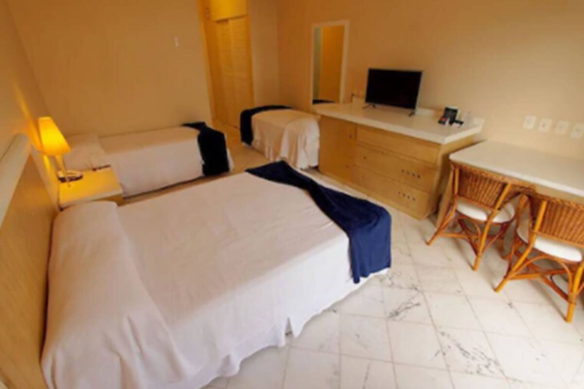 Una habitación de hotel con dos camas, un escritorio, una silla, un televisor y un aparador.